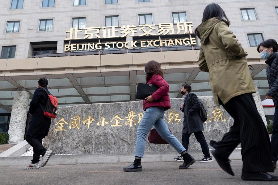 People walk past the Beijing Stock Exchange on its first day of trading in Beijing, China, on 15 November 2021. (Wang Zhao/AFP)