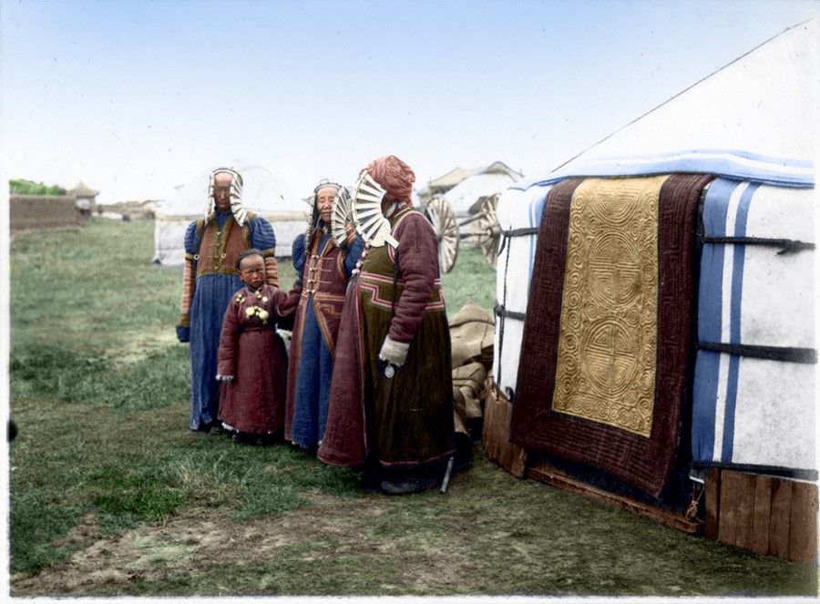 Mongolian yurts, home to nomadic tribes, stand in the vast grasslands of Mongolia, 1930s. Beside the yurts, womenfolk in formal wear welcome guests.