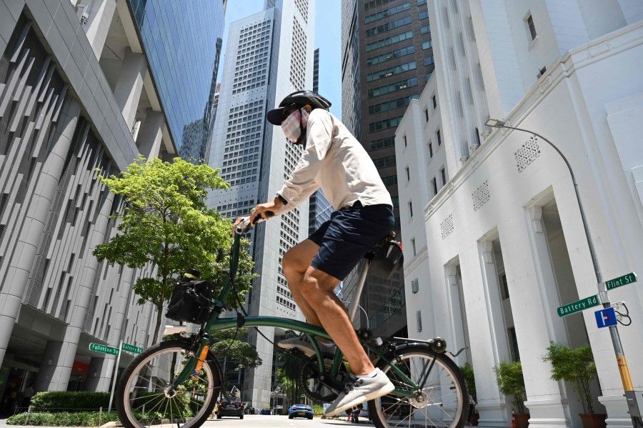 A man rides a bicycle along a street at the Raffles Place financial business district in Singapore on 20 April 2021. (Roslan Rahman/AFP)