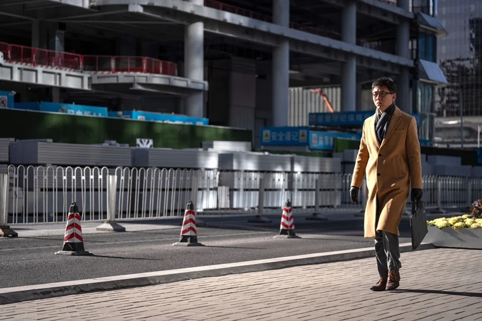 A pedestrian passes a construction site in Beijing, China, on 30 December 2024. (Na Bian/Bloomberg)