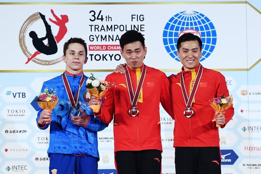 Gold medalist Lei Gao of China and bronze medalist Dong Dong of China, with silver medalist Ivan Litvinovich of Belarus, pose on the podium of the men's trampoline event at the World Trampoline Gymnastics Championships at the Ariake Gymnastics Centre in Tokyo, December 2019. (Charly Triballeau/AFP)