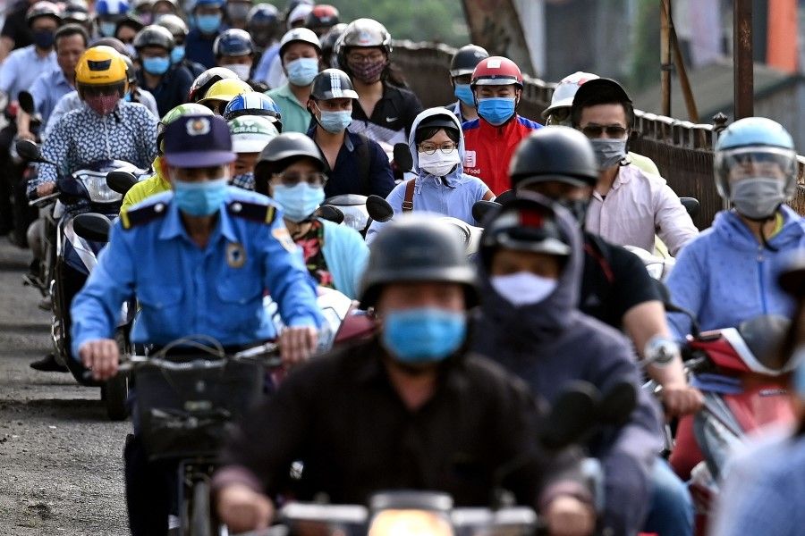 Morning commuters wearing face masks, amidst concerns about the Covid-19 coronavirus, ride past in Hanoi on 4 May 2021. (Manan Vatsyayana/AFP)