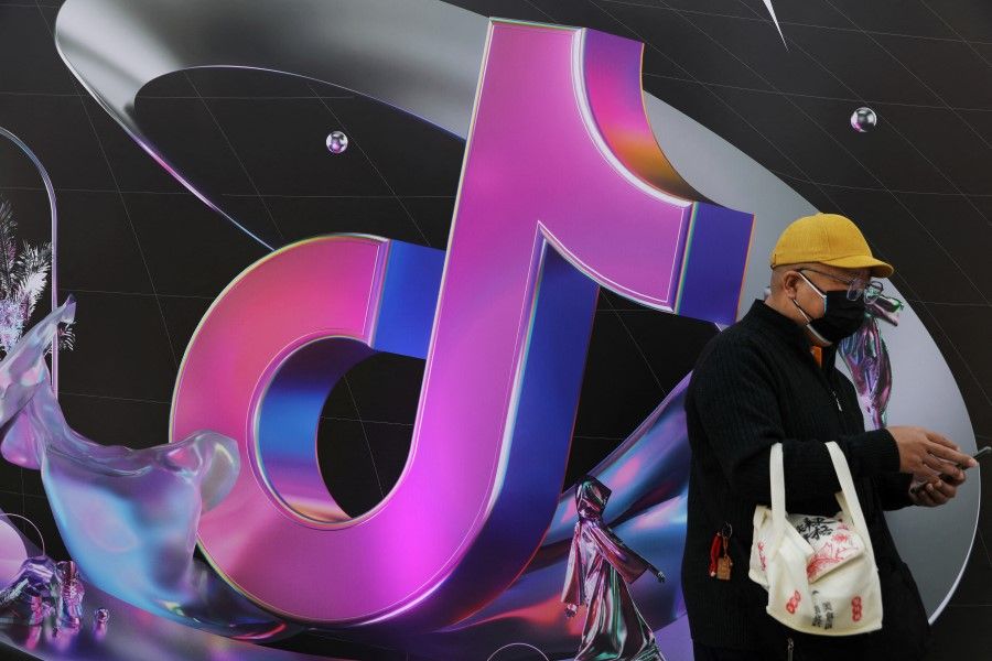 A man stands near a sign of ByteDance app Douyin during China Fashion Week, in Beijing, China, 31 March 2021. (Tingshu Wang/Reuters)