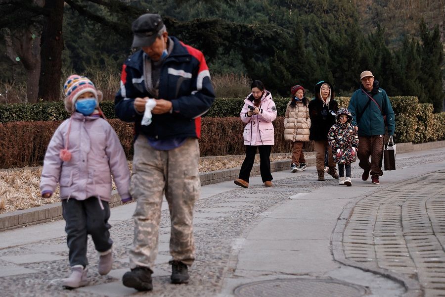 Elderly people walk with children at a park in Beijing, China, on 12 January 2024. (Tingshu Wang/Reuters)