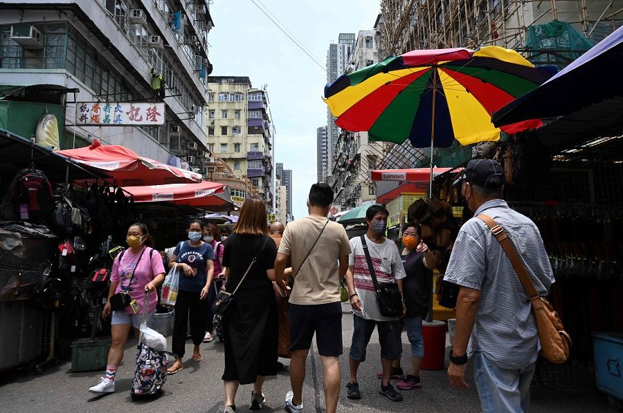 People walk around a busy shopping district in the Kowloon area of Hong Kong on 20 June 2021. (Peter Parks/AFP)