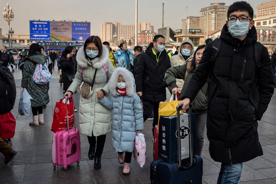 The outbreak of the Wuhan coronavirus is rapidly escalating. In this photo taken on 21 January 2020, people wearing protective masks are seen arriving at Beijing railway station to head home for the Lunar New Year. (Nicolas Asfouri/AFP)