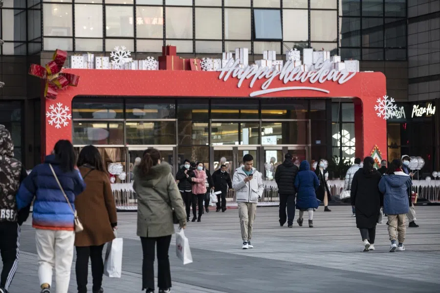 Shoppers walk past a Happy New Year decoration outside a mall in Shanghai, China on 19 December 2020. China pulled further ahead of other major economies in November as industrial output and retail sales strengthened, reinforcing expectations of healthy growth in 2021. (Qilai Shen/Bloomberg)