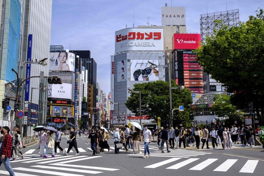 People cross a street during the "golden week" holiday in Tokyo's Shinjuku area on 5 May 2022. (Charly Triballeau/AFP)