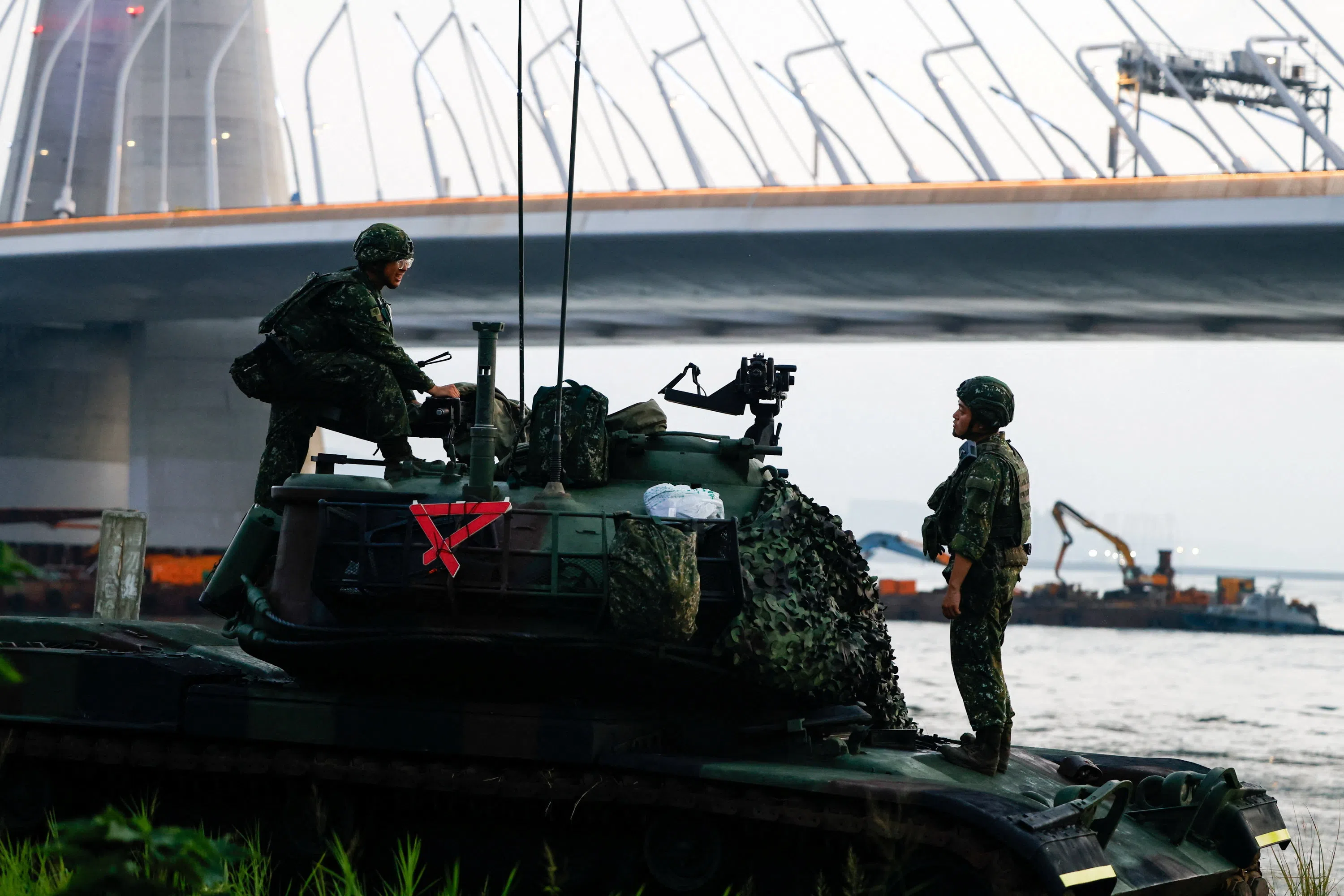 Military personnel stand on a tank as they are deployed near the Danjiang Bridge during the annual Han Kuang military exercise in New Taipei City, Taiwan, on 6 August 2026.
