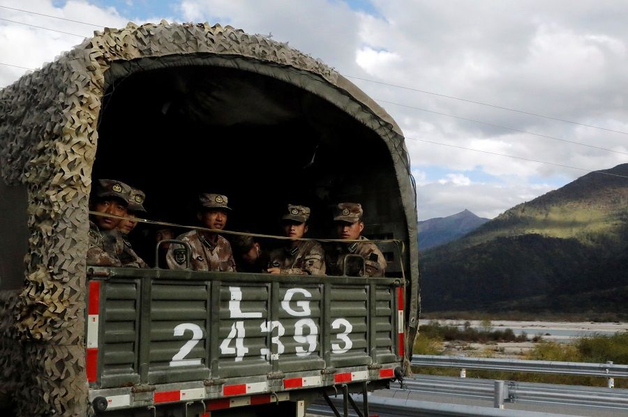 Chinese soldiers of the People's Liberation Army (PLA) sit on the back of a truck on the highway to Nyingchi, Tibet Autonomous Region, China, 19 October 2020. (Thomas Peter/Reuters)