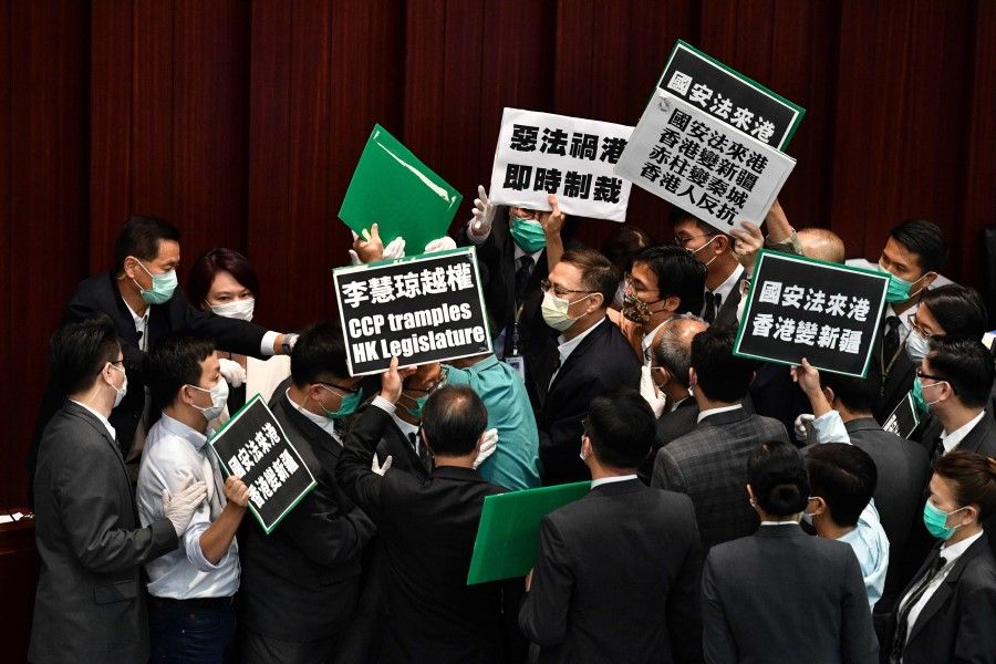 Hong Kong pro-democracy lawmakers holding up placards are blocked by security as they protest during a House Committee meeting concerning the second reading of a national anthem bill, at the Legislative Council in Hong Kong, 22 May 2020. (Anthony Wallace/AFP)