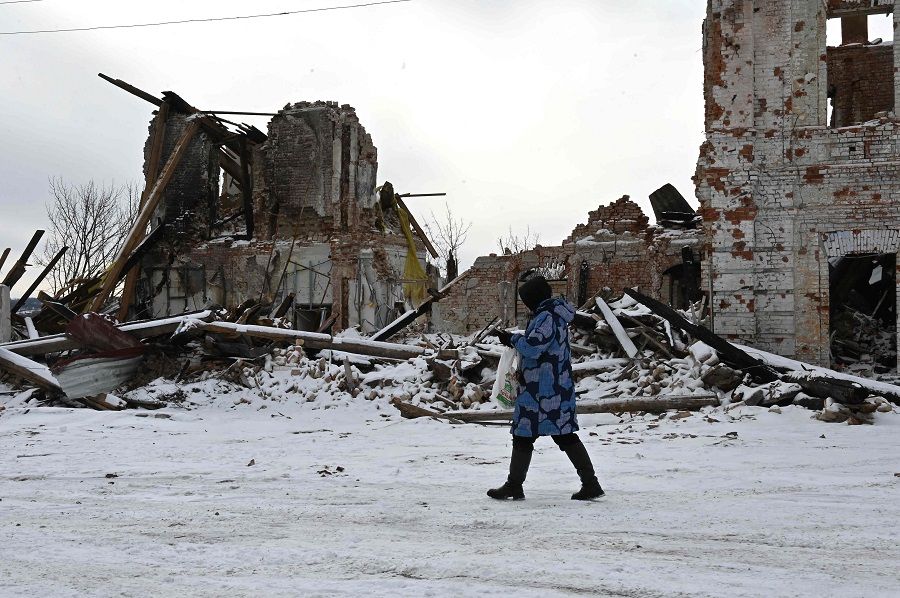 A local resident walks past a building destroyed by shelling, in Kupiansk, Kharkiv region, Ukraine, on 13 February 2023. (Sergey Bobok/AFP)