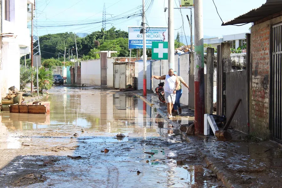 People walk through a flooded street in Esmeraldas, Ecuador, on 5 June 2023. (Luis Cheme/AFP)