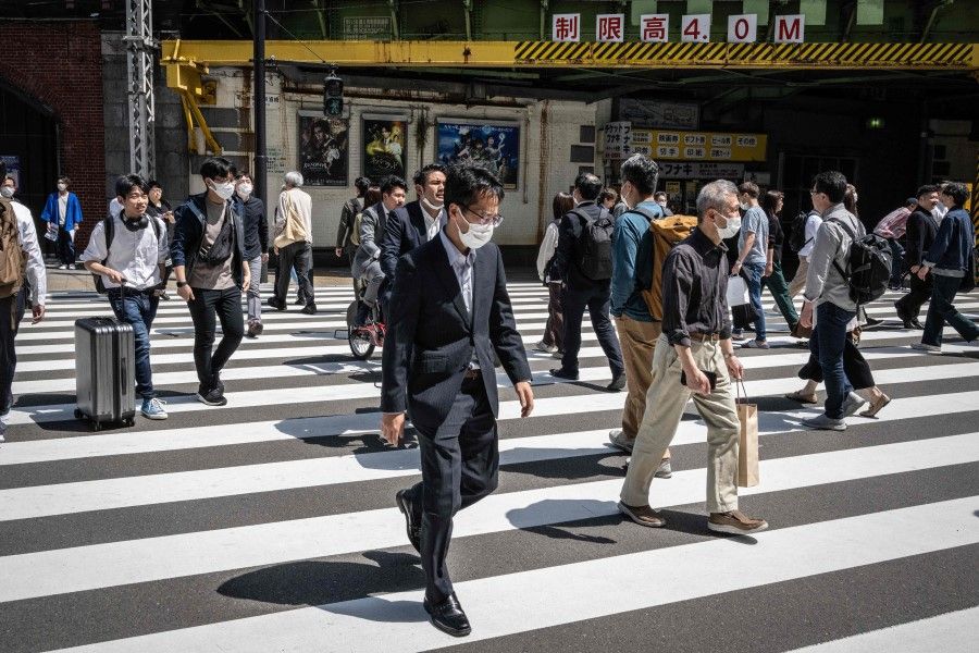 People cross a street in Yurakucho district of Tokyo on 28 April 2023. (Yuichi Yamazaki/AFP)