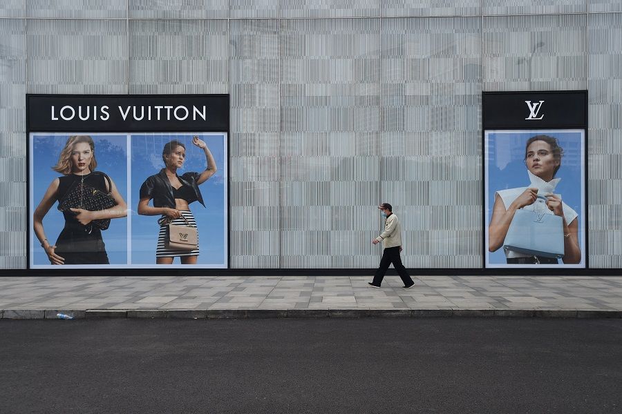A man wearing a face mask walks past a store of French luxury brand Louis Vuitton at a shopping mall in Wuhan, Hubei province, China, 25 February 2020. (Stringer/Reuters)
