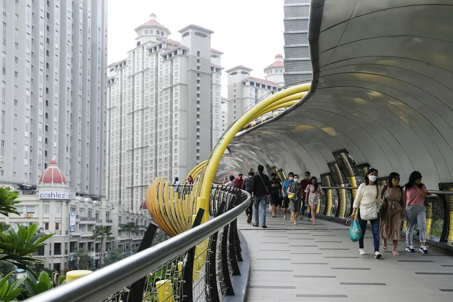 People wearing protective face masks walk on a bridge at a shopping mall in Jakarta, Indonesia, 30 October 2021. (Ajeng Dinar Ulfiana/Reuters)