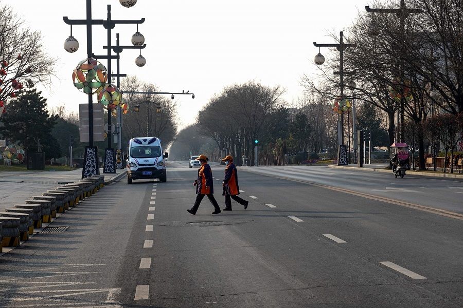 People cross a road in Xi'an, Shaanxi province, China, on 31 December 2021, amid a Covid-19 coronavirus lockdown. (AFP)