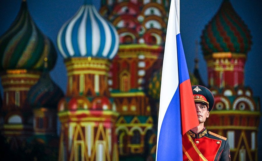 A Russian soldiers stands with a national flag at the Red Square during the Spasskaya Tower International Military Music Festival at the Red Square in Moscow, Russia, on 26 August 2022. (Alexander Nemenov/AFP)