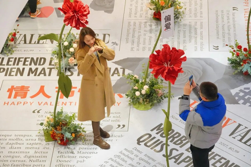 ​A couple taking photos with an installation of flowers at a shopping mall during Valentine's Day in Yantai in China's eastern Shandong province on 14 February 2022. (AFP)