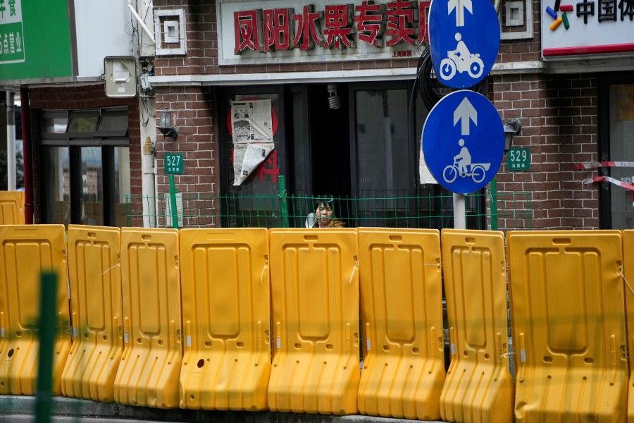 A resident looks on behind barriers at a fruit shop, during lockdown, amid the Covid-19 pandemic, in Shanghai, China, 16 May 2022. (Aly Song/Reuters)