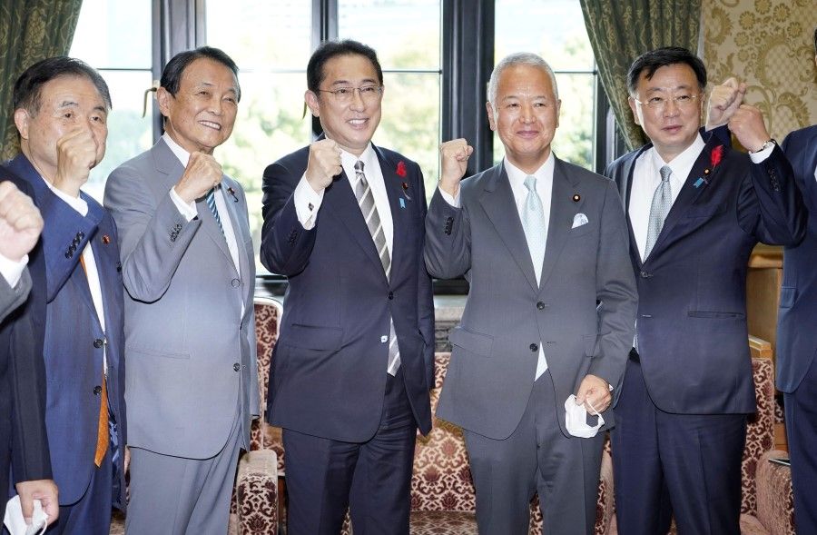 Japanese Prime Minister Fumio Kishida (centre) poses for photos with LDP executives at the parliament building after the House of Representatives was dissolved for a general election at the end of the month, in Tokyo, Japan, 14 October 2021 in this photo taken by Kyodo. (Kyodo via Reuters)