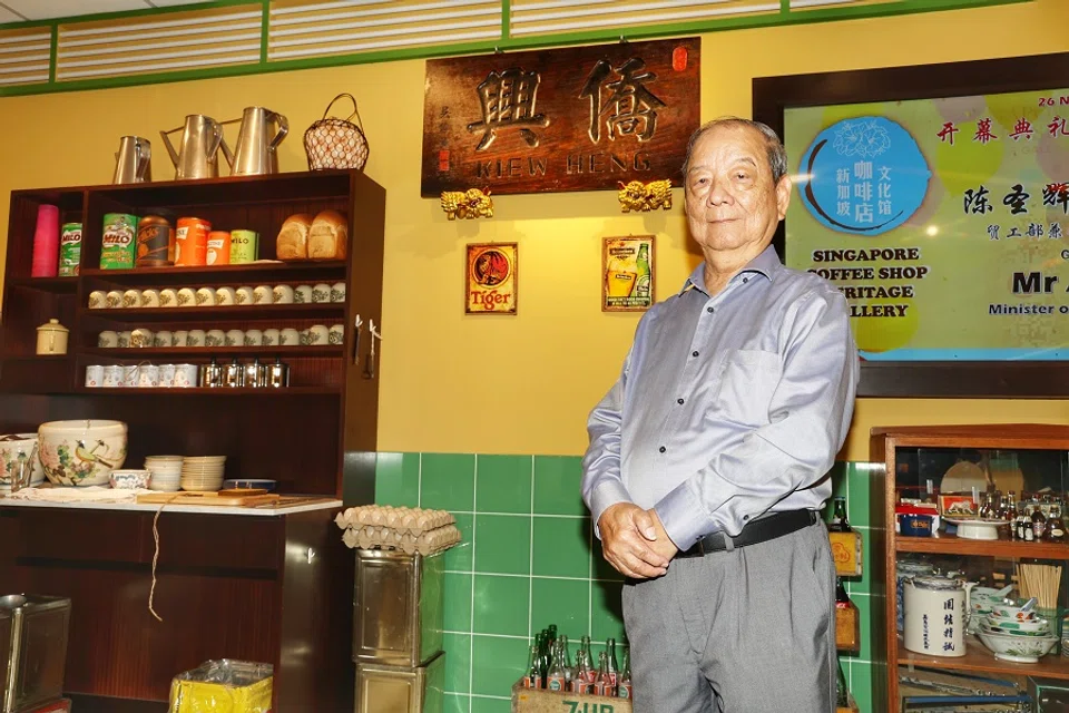 Choo Ee Choo ran a coffee stall in his younger days. The signboard of the “Kiew Heng” (侨兴) coffee shop, the name of his father-in-law’s coffee shop, hangs on the wall behind him. (Tay Yee Ming/SPH Media)
