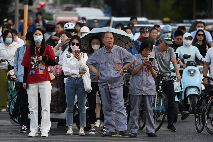People wait to cross a road at rush hour in Beijing, China, on 22 May 2023. (Greg Baker/AFP)