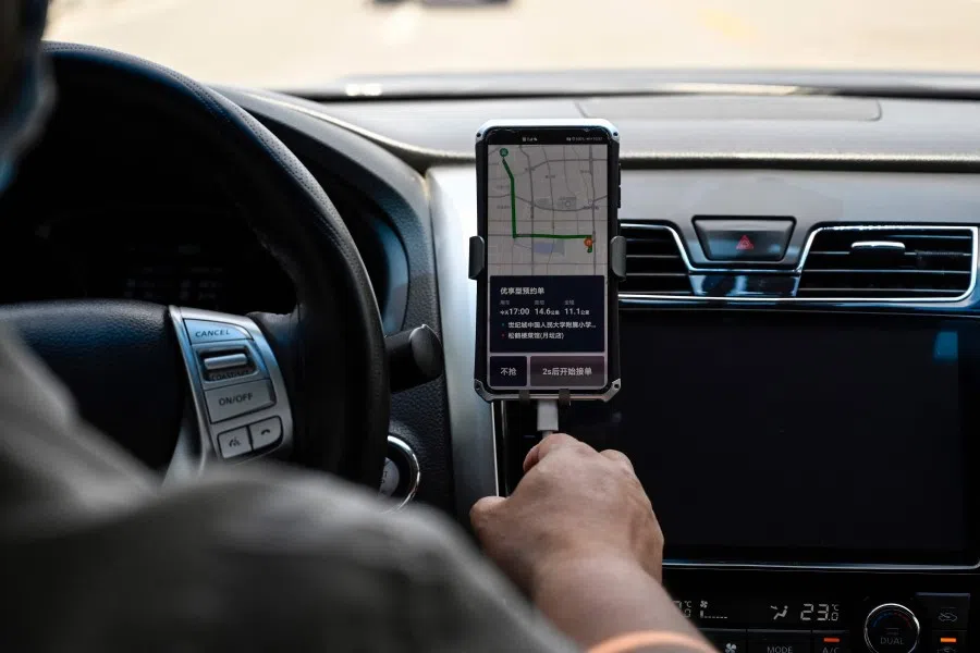 A driver uses the Didi Chuxing ride-hailing app on his smartphone while driving along the street in Beijing on 2 July 2021. (Jade Gao/AFP)