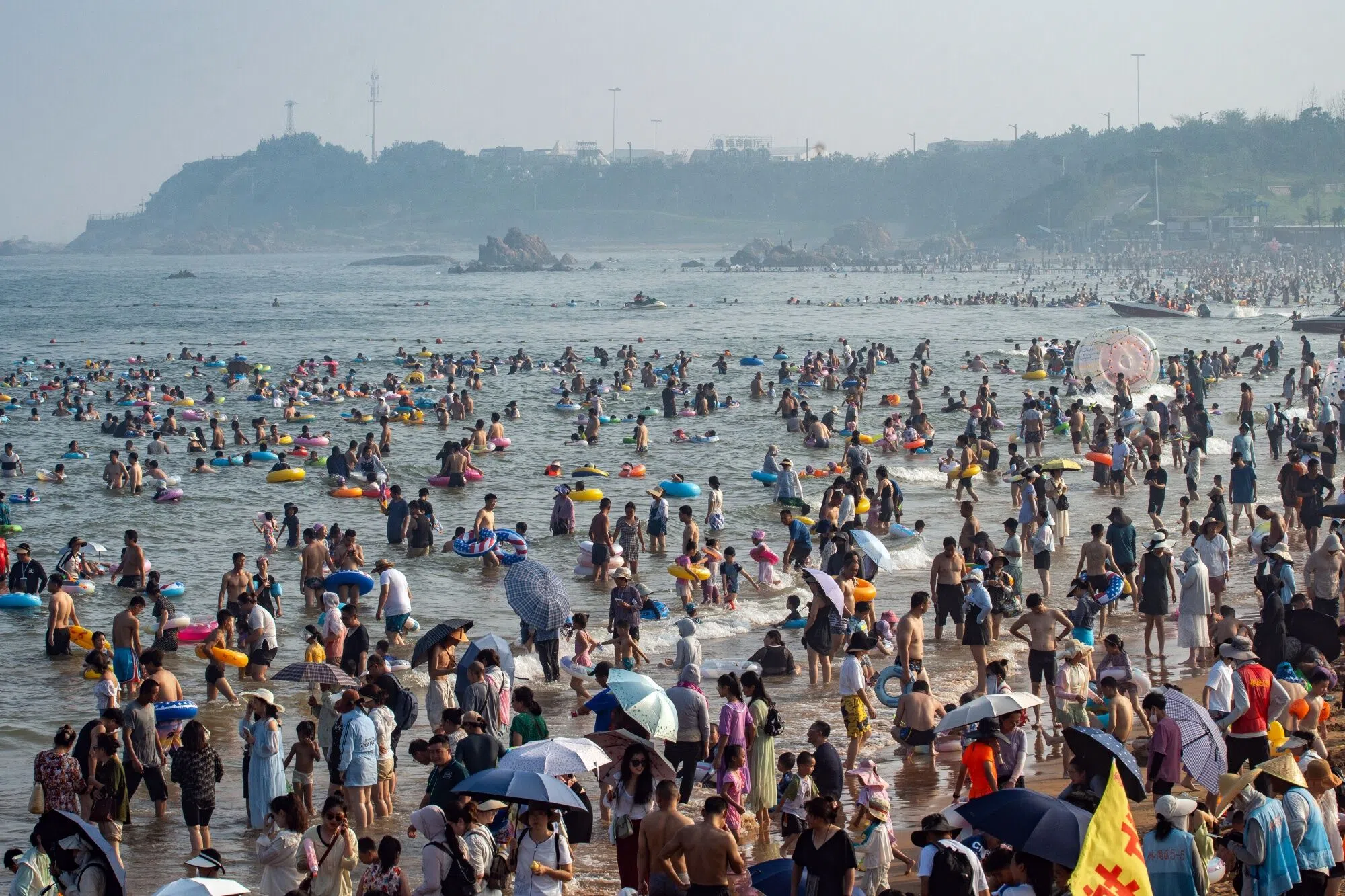 Visitors at a beach in Qingdao, Shandong province, China, on 4 August 2024. China has announced a 20-step action plan to get people to spend more, but offered little in the way of financial incentives to rev up domestic demand. (Andrea Verdelli/Bloomberg)