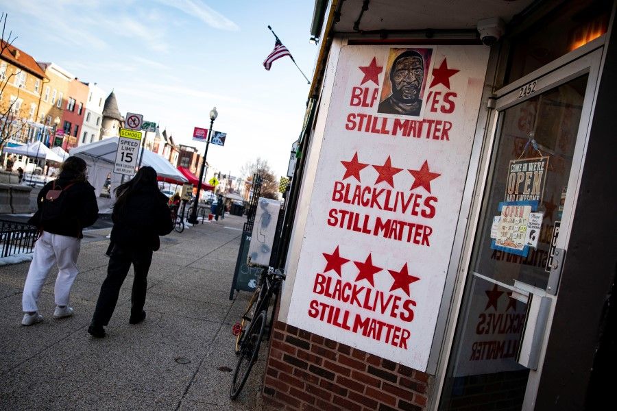 People walk past a sign about the Black Lives Matter movement in the Adams Morgan neighborhood, in Washington, U.S., 21 February 2021. (Al Drago/Reuters)