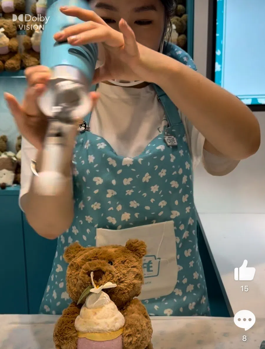 An employee at Jellycat’s Shanghai pop-up store “squeezes” whipped cream onto a plush toy. (Screenshot from Weibo video)