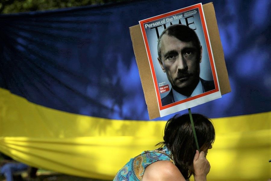 A pro-Ukraine demonstrator holds a sign with Putin depicted as Hitler during a protest against Russian invasion of Ukraine, in Sao Paulo, Brazil, 9 April 2022. (Carla Carniel/Reuters)