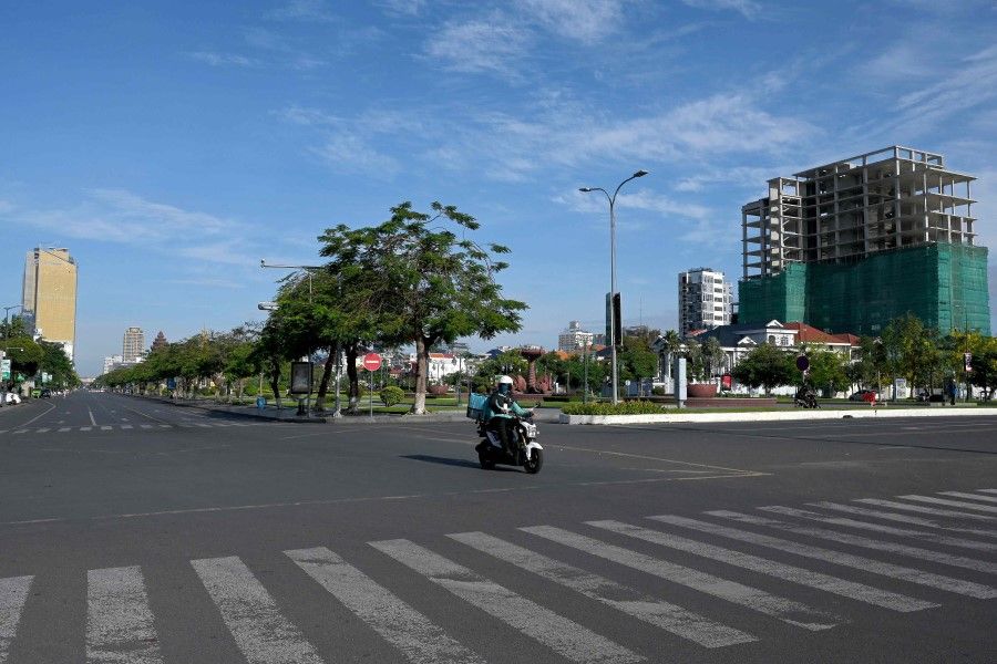 A food delivery motorist rides on a street empty of traffic due to lockdown restrictions introduced to try to halt a surge in cases of the Covid-19 coronavirus in Phnom Penh on 25 April 2021. (Tang Chhin Sothy/AFP)