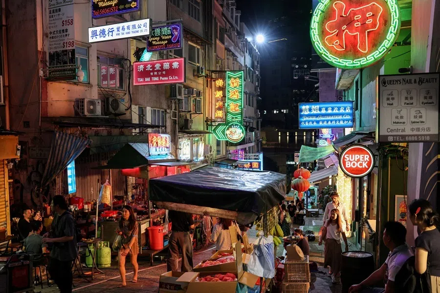 People walk along a street in Hong Kong's Soho district, decorated with temporary neon lights and market stalls for a film production, China, 13 August 2026.