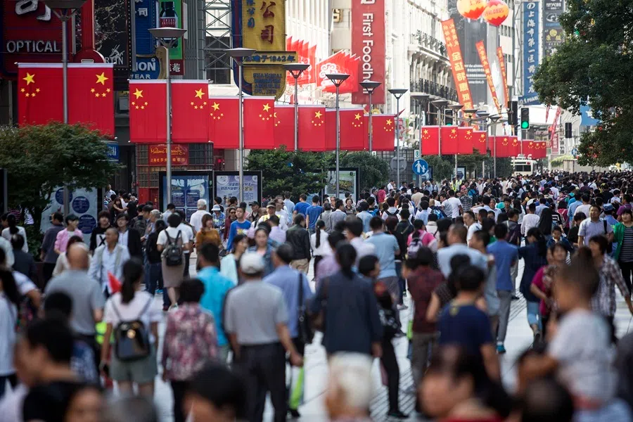 Pedestrians walk past Chinese national flags displayed along the Nanjing Road pedestrian street in Shanghai, China, on 2 October 2015.