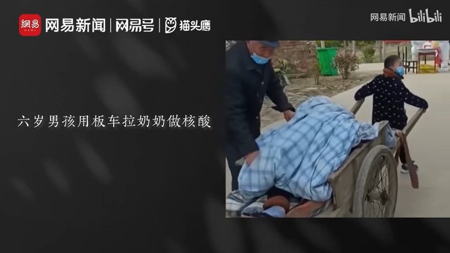 A screen grab from the video released by NetEase, showing a boy pulling his severely ill grandmother on a wooden cart to get tested for Covid. (Internet)