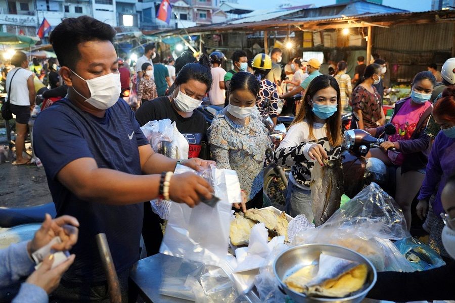 People wearing protective face masks buy groceries at a fresh market at a temple in Phnom Penh, Cambodia, 14 April 2021. (Cindy Liu/Reuters)