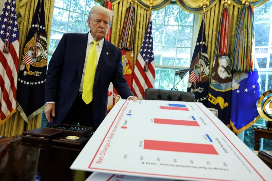 US President Donald Trump holds a board, as he makes an announcement on the economy, in the Oval Office at the White House in Washington, DC, US, on 7 August 2025.