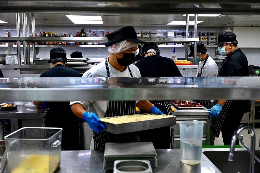 This photo taken on 18 August 2021 shows workers from a Taiwanese company that makes delivery-only food, preparing meals at one of their locations in Taipei, Taiwan. (Sam Yeh/AFP)