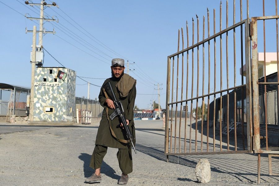 In this photo taken on 18 February 2022, a Taliban fighter stands guard at the entrance gate of the Afghan-Iran border crossing bridge in Zaranj, Afghanistan. (Wakil Kohsar/AFP)