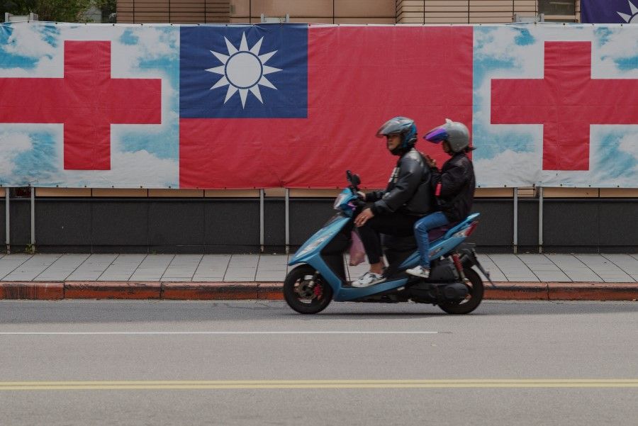 Two people on a motorcycle ride past Taiwan's flag in Taipei on 21 March 2023. (Sam Yeh/AFP)
