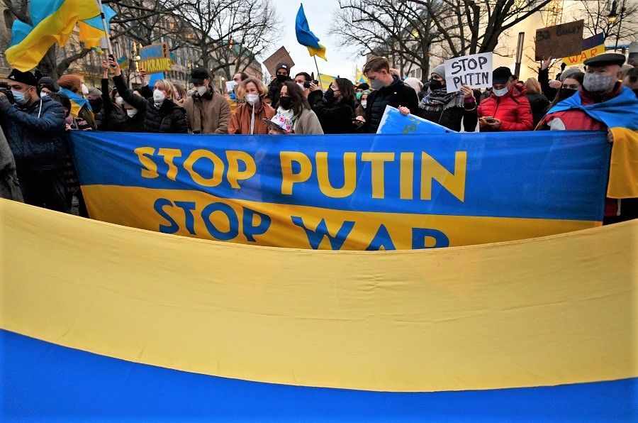 Pro-Ukraine demonstrators hold flags and placards during a demonstration in front of the Russian embassy in Berlin, Germany, on 22 February 2022, following Russia's recognition of eastern Ukrainian separatists. (John Macdougall/AFP)