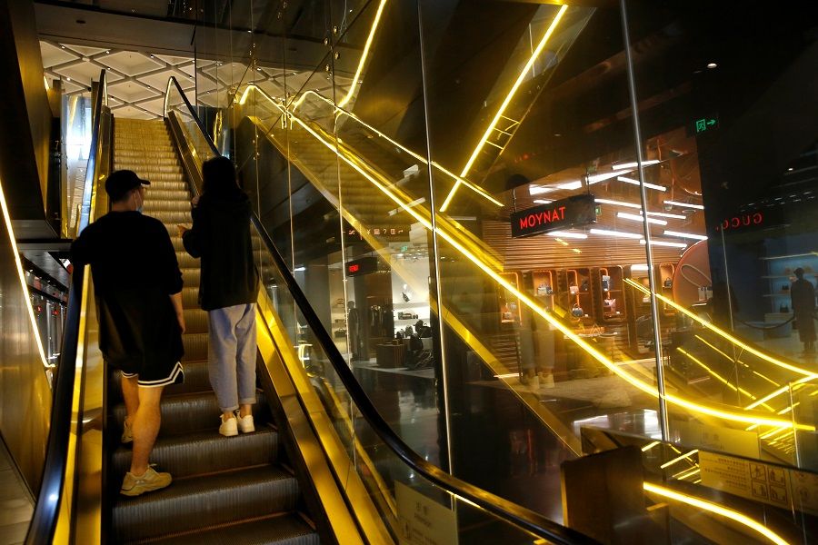 People wearing face masks ride on an escalator inside a shopping mall in Beijing, China, 23 September 2020. (Tingshu Wang/Reuters)