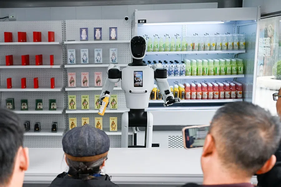 A robot works at a booth along a business street in Beijing on 22 October 2025. (Wang Zhao/AFP)