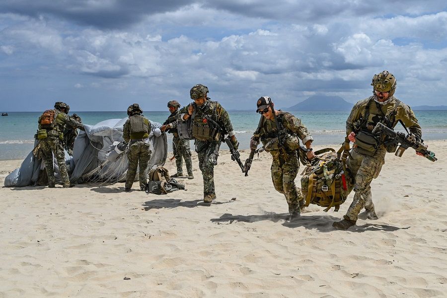 Soldiers carry away their parachutes after landing on a beach as they participate in a military free fall during the US-Philippines Balikatan joint military exercise at San Vicente in Palawan on 30 April 2024.  (Jam Sta Rosa/AFP)