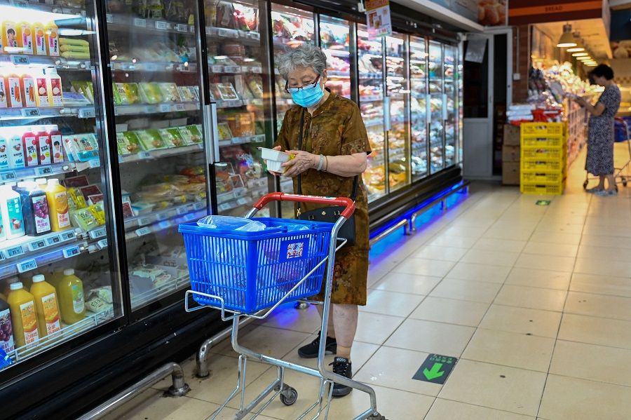 A woman shops for frozen items at a supermarket in Beijing on 13 August 2023. (Pedro Pardo/AFP)