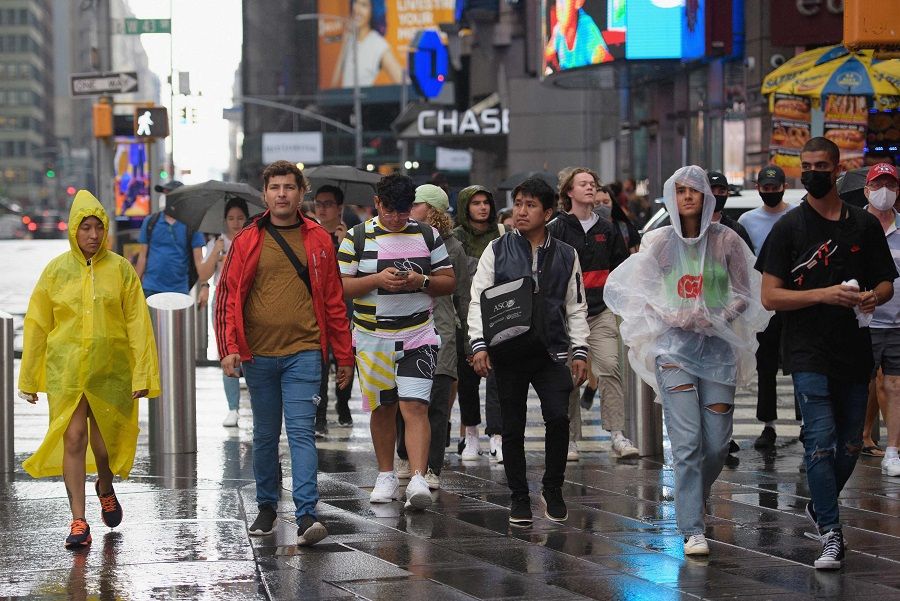 People walk through Times Square during rainfall in New York City, US on 23 August 2021. (Angela Weiss/AFP)