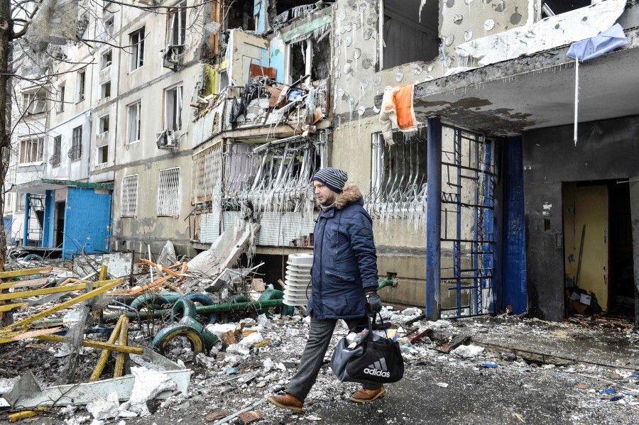 A man leaves an apartment building damaged after shelling the day before in Ukraine's second biggest city of Kharkiv on 8 March 2022. (Sergey Bobok/AFP)