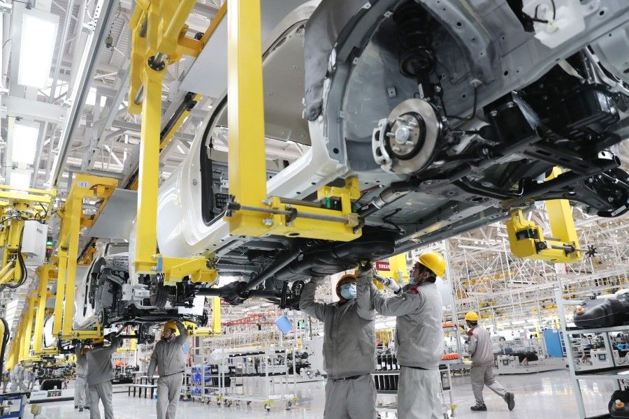 This photo taken on 14 January 2023 shows employees working on a car assembly line at a Beijing Automotive factory in Qingdao, in China's eastern Shandong province. (AFP)