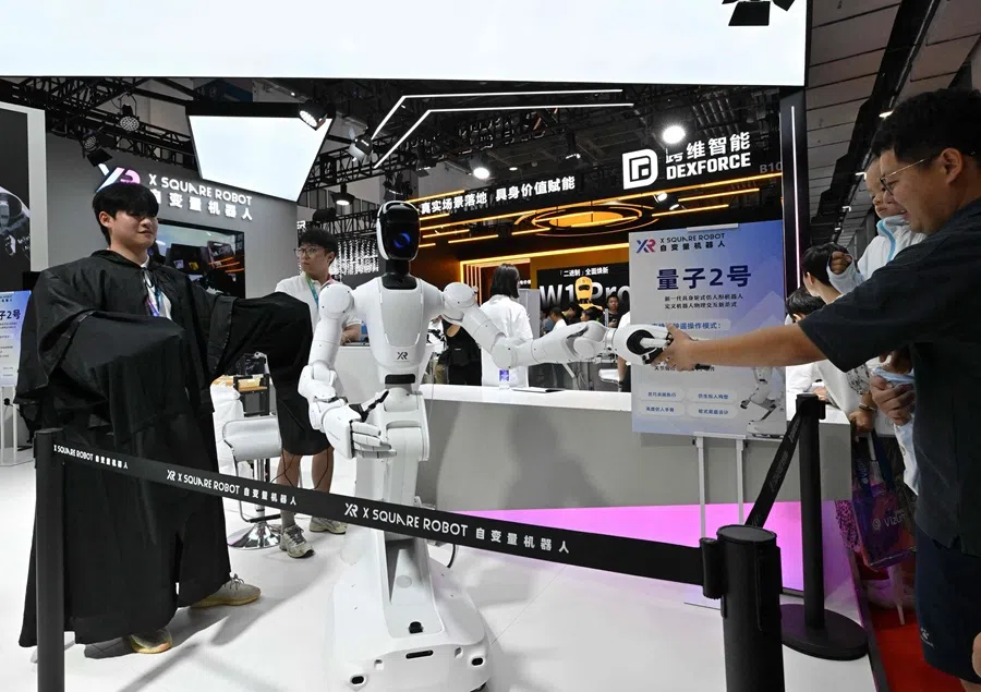 A man (right) interacts with a robot during an exhibition as part of the 2025 World Robot Conference in Beijing on 8 August 2025. (Adek Berry/AFP)